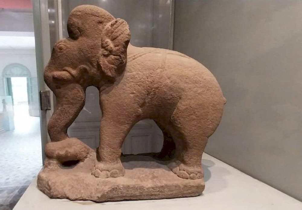 The 7th-8th century sandstone elephant statue features a straight gaze, curled trunk, and Cham-style carvings, including a diamond motif 